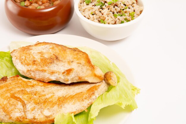 Frango grelhado em um prato com salada de arroz e feijão foto de cima