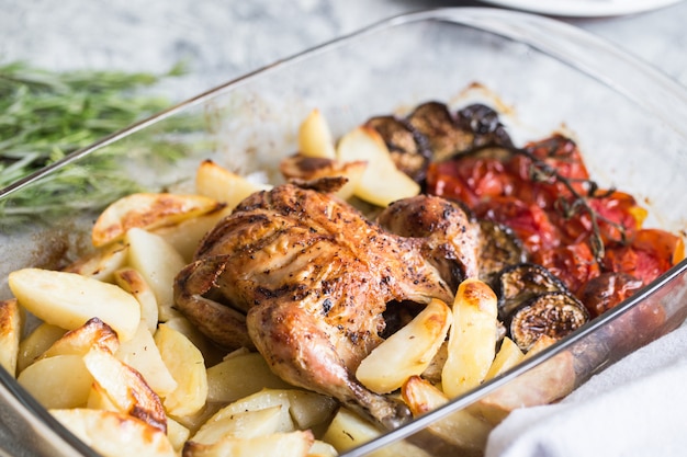 Frango inteiro assado com batatas, berinjela e tomate cereja. jantar saudável