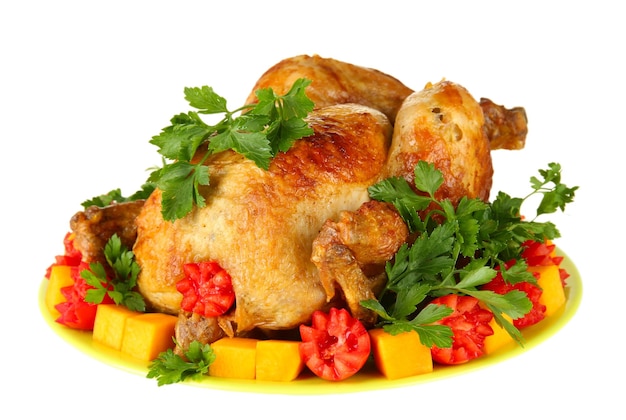 Frango inteiro assado com legumes em um prato verde isolado no branco