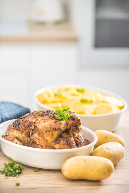 Frango inteiro assado em uma tigela de porcelana com batatas.