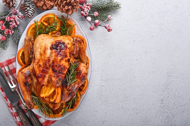 Frango inteiro assado ou assado com alecrim e laranjas, caseiro para jantar em família tradicional de natal na mesa rústica cinza pedra. vista superior com espaço de cópia.