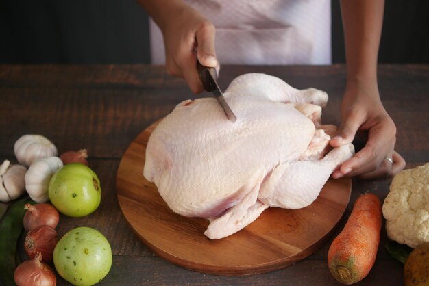 Frango inteiro cru e legumes em fundo de azulejos