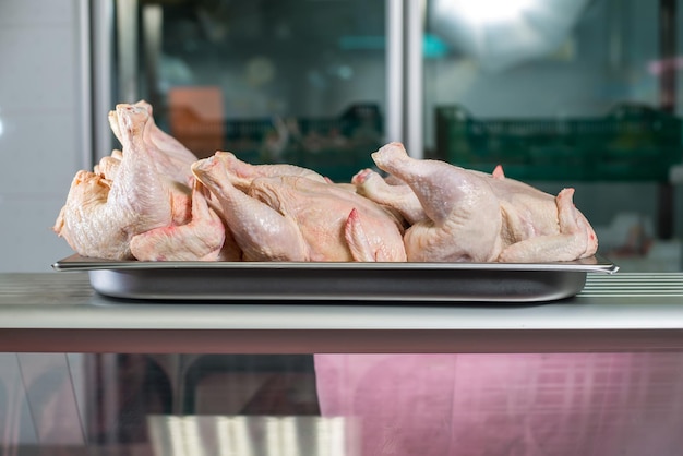 Frango inteiro cru em perfil na bandeja de ferro