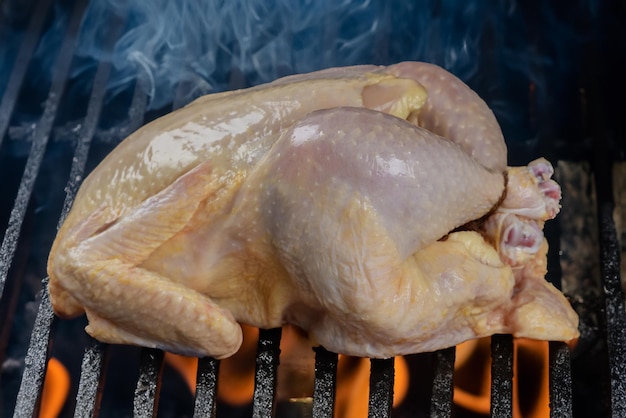 Frango inteiro cru na grelha de carvão