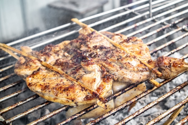 Frango inteiro tailandês grelhado com carvão na rua.