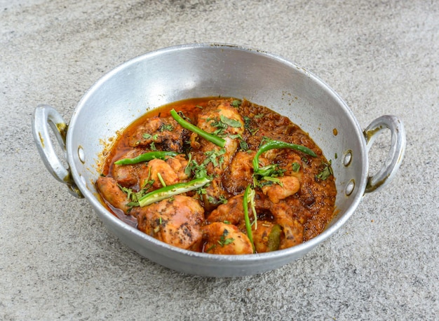 Frango karahi korma com molho servido em prato isolado na vista superior de fundo cinza da comida de especiarias paquistanesas e indianas