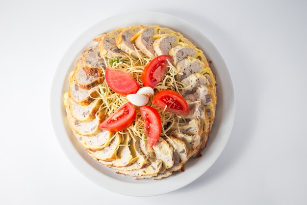 Frango picado com macarrão, tomate e ovos de cana no prato.