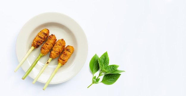 Frango picado grelhado com pasta de curry e creme de coco em espetos de capim-limão