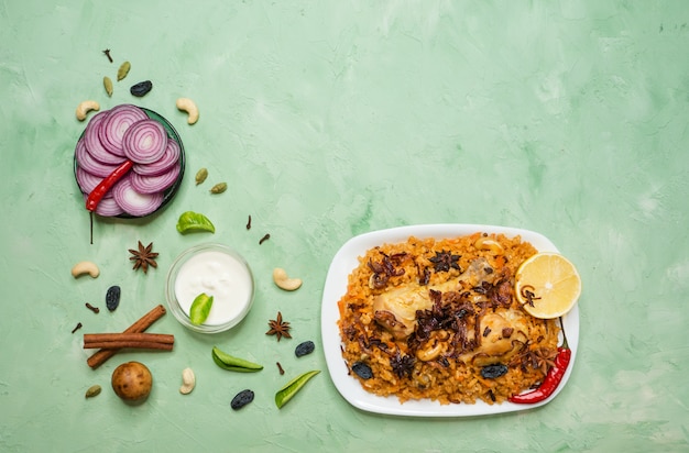 Frango picante delicioso Biryani em uma tigela branca sobre fundo verde, comida indiana ou paquistanesa.