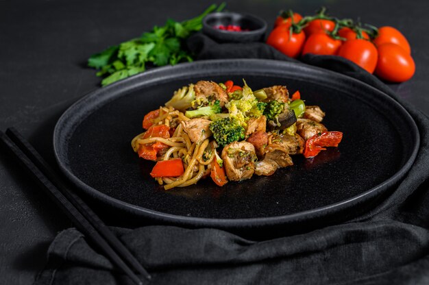 Frango salteado com legumes sause de soja, wok. Comida asiática tradicional. mesa de pedra preta