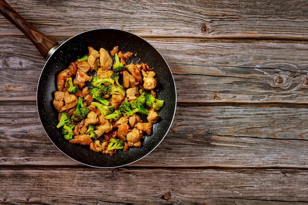 Frango salteado delicioso prato chinês com brócolis na wok. Copie o espaço.