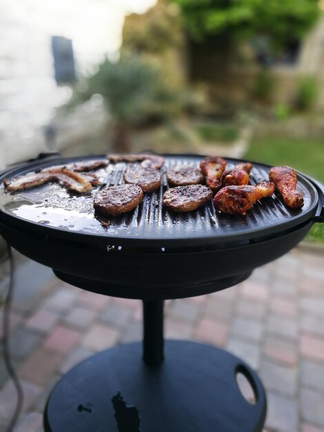 Frango sendo cozido em uma grelha de churrasco no quintal