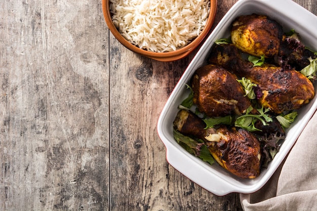 Frango tandoori assado com arroz basmati na mesa de madeira. Vista do topo.