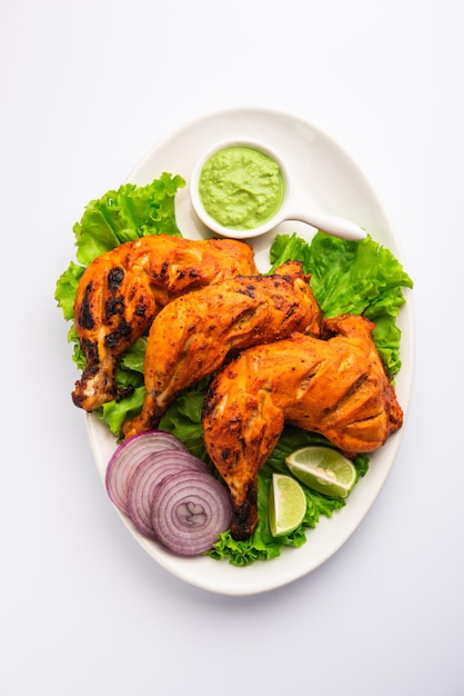 Frango Tandoori é um prato de frango preparado assando frango marinado em iogurte e temperos em tandoor ou forno de barro, servido com cebola e chutney verde