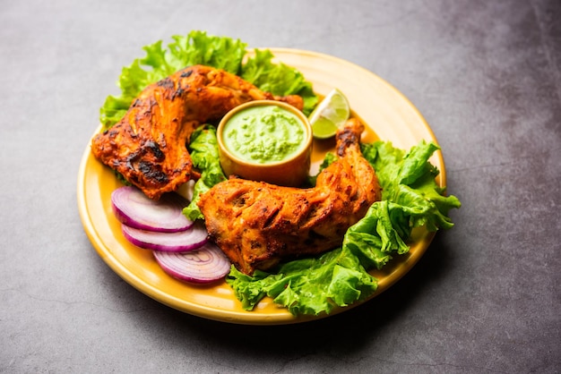 Frango tandoori é um prato de frango preparado assando frango marinado em iogurte e temperos em tandoor ou forno de barro, servido com cebola e chutney verde