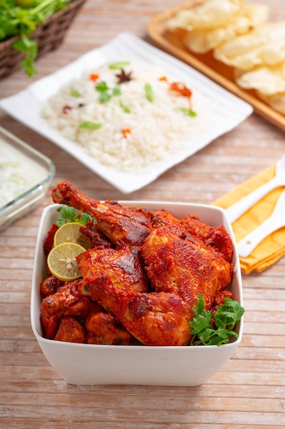 Frango Tandoori picante guarnecido com folha de coentro em tigela quadrada branca