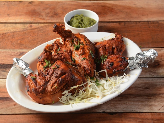 Frango tandoori preparado assando frango marinado em iogurte e especiarias em um tandoor servido sobre um foco seletivo de fundo rústico de madeira