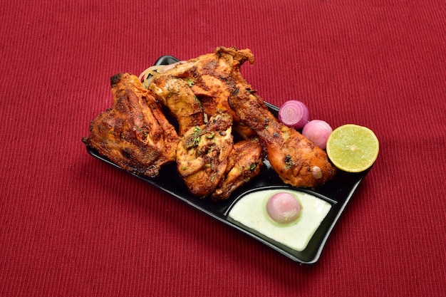 Frango tandoori servido com cebola e chutney no prato