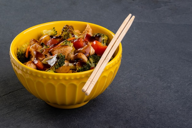 Frango yakissoba em uma tigela amarela.