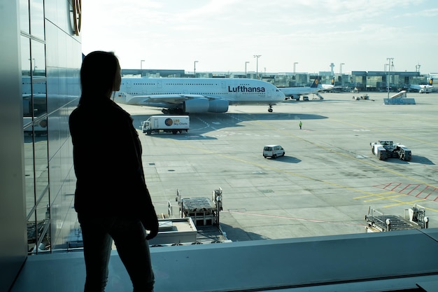 Frankfurt am Main, Alemania - 11 de octubre de 2015: silueta de niña mira aviones en el suelo del aeródromo en un día soleado. Mujer en aeropuerto. Viajando por aire. Aviación, transporte aéreo. Pasión por los viajes, vacaciones, viaje.