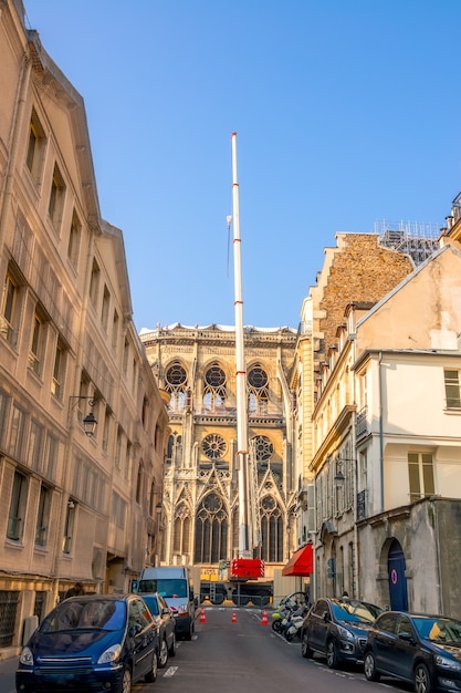 Frankreich. Sonniger Sommertag in Paris. Schmale Straße mit geparkten Autos. Crane stellt Notre Dame nach einem Brand wieder her