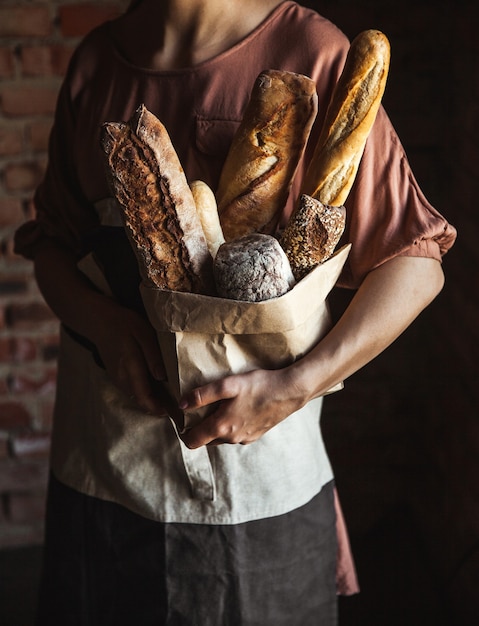 Französische Baguettes in den weiblichen Händen auf einem schwarzen Hintergrund. hausgemachtes Backen