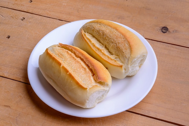 Französische Brötchen. Brasilianisches Brot auf einem weißen Teller auf Holztisch.