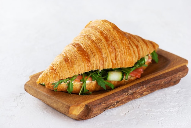 Französische Croissant-Sandwiches mit Lachs-Frischkäse und Rucola auf Holzbrett