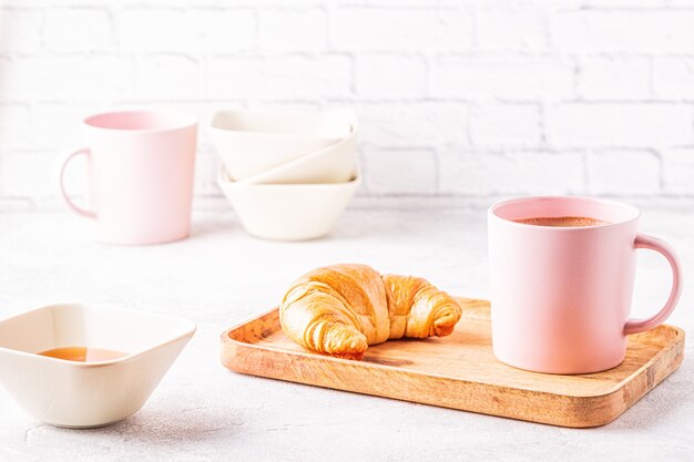 Französische Croissants und eine Tasse Kaffee auf einem Holztablett.