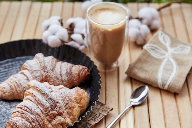 Französische frische Croissants Tasse Latte und Baumwolle auf der Terrasse Pastellfarbener Hintergrund Herbstliche Gemütlichkeit