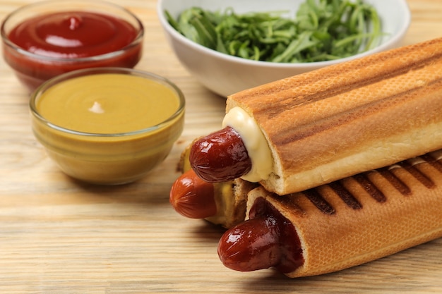 Französische Hotdogs. Leckere Hotdogs und Ketchup und Senf auf einem natürlichen Holztisch. Fastfood-Streetfood. Würstchen in einem Brötchen.