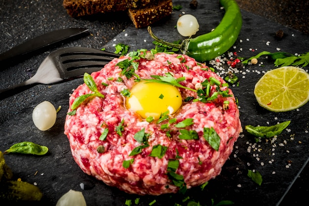 Französische Küche, Tartar vom Rind mit rohem Wachtelei, eingelegter Gurke und Zwiebeln, frischen Kräutern, Brot