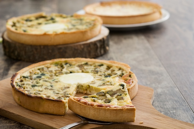 Französische Quiche Lothringen mit Gemüse auf einem rustikalen Holztisch