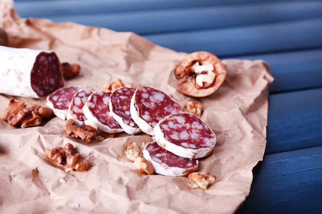 Französische salami und walnüsse auf bastelpapier auf dunkelblauer holzoberfläche