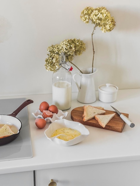 Französische Toast zum Frühstück, Brot, Eier, Milch auf einem hellen Tisch in einer gemütlichen Küche im minimalistischen Stil