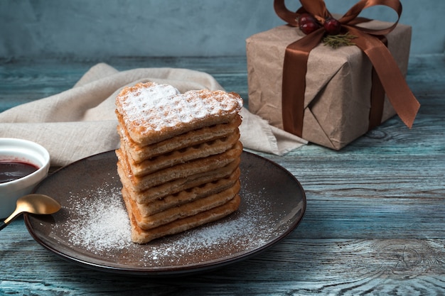 Französische Waffeln und Geschenkbox auf hölzernem Hintergrund.