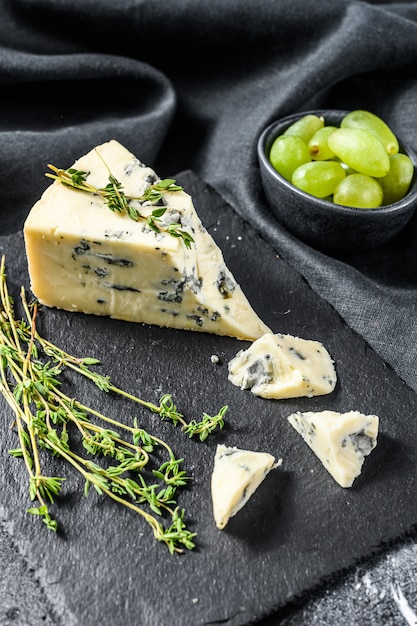 Französischer Gorgonzola-Käse mit Trauben. Schwarzer Hintergrund. Draufsicht