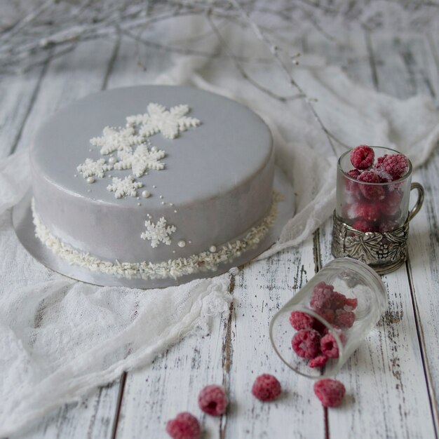 Französischer Himbeercremekuchen mit Dekoration des neuen Jahres auf weißem Holztisch.