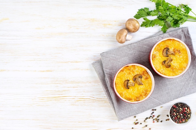 Französischer Julienne-Auflauf mit Hähnchen und Champignons in Portionsramekin auf weißem Hintergrund