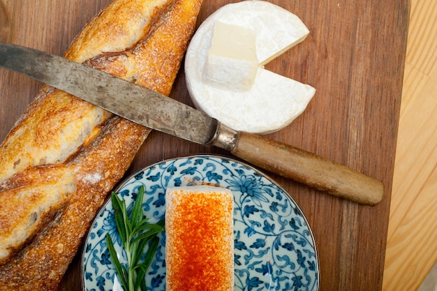 Französischer Käse und frisches Baguette auf einem Holzschneider