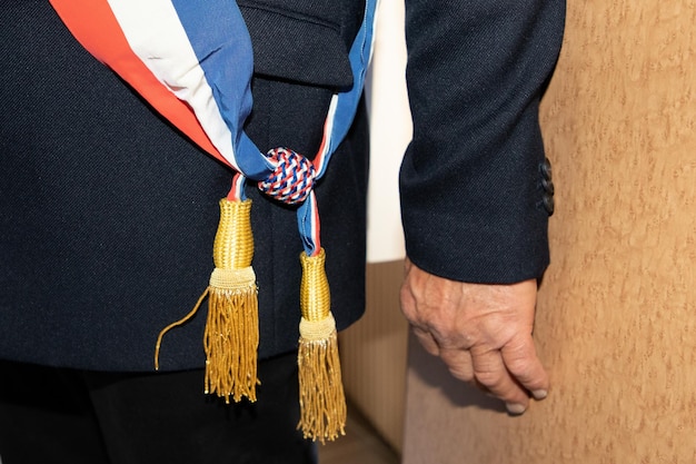 Französischer Stadtbürgermeister mit dreifarbigem Schal mit französischer Flagge während der offiziellen Feier