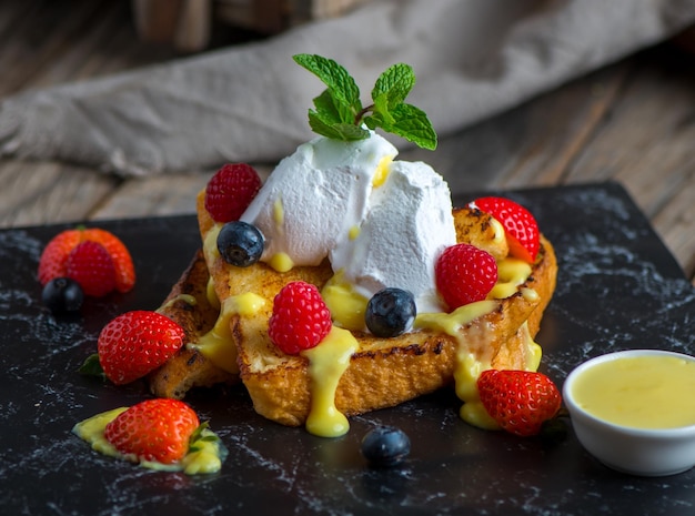 Französischer Toast mit Erdbeer-Brombeer-Creme und Basilikum serviert in einem Gericht isoliert auf Schneidebrett Seitenansicht des Frühstücks auf Holzhintergrund