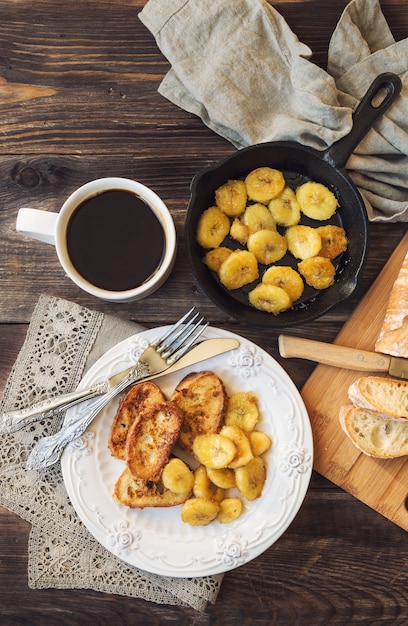 Französischer Toast mit gebratenen Bananen zum Frühstück auf rustikalem hölzernem Hintergrund. Draufsicht.