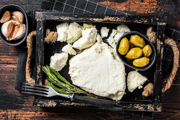 Französischer Ziegenweichkäse in einem Tablett mit Oliven und Rosmarin Holzhintergrund Draufsicht