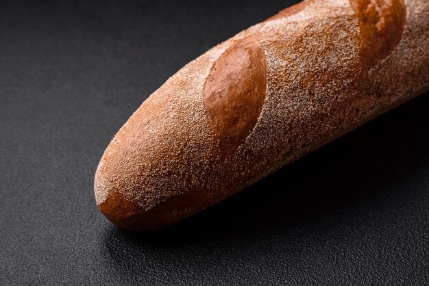 Französisches Baguette-Brot auf einem dunklen Beton-Hintergrund, mit dem man zu Hause köstliche Bruschetta zubereitet