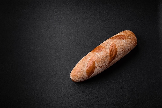 Foto französisches baguette-brot auf einem dunklen beton-hintergrund, mit dem man zu hause köstliche bruschetta zubereitet