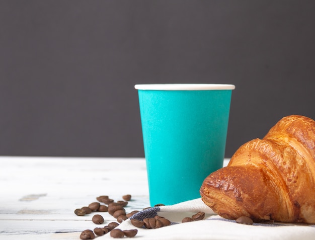 Französisches Croissant mit Kaffee zum Mitnehmen in Pappbecher. Freier Kopierplatz.