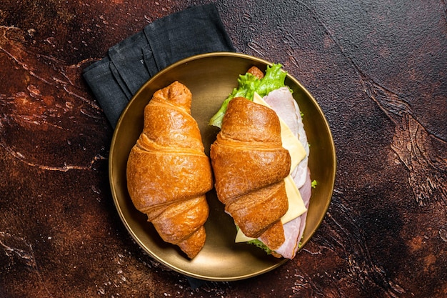 Französisches Croissant-Sandwich mit Kopfsalat, Käsetomaten und Schinken Dunkler Hintergrund Draufsicht