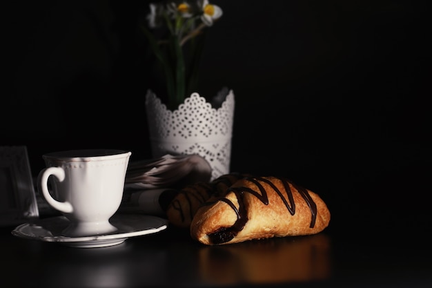 Französisches Frühstück auf dem Tisch. Kaffee-Croissant mit Schokolade und eine Karaffe mit Sahne. Frisches Gebäck und entkoffeinierter Kaffee.