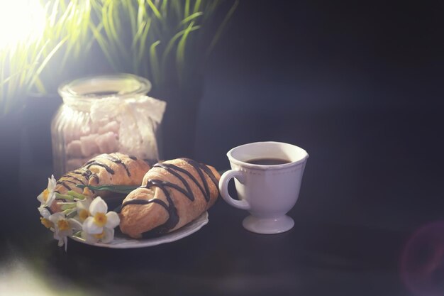 Französisches Frühstück auf dem Tisch. Kaffee-Croissant mit Schokolade und eine Karaffe mit Sahne. Frisches Gebäck und entkoffeinierter Kaffee.